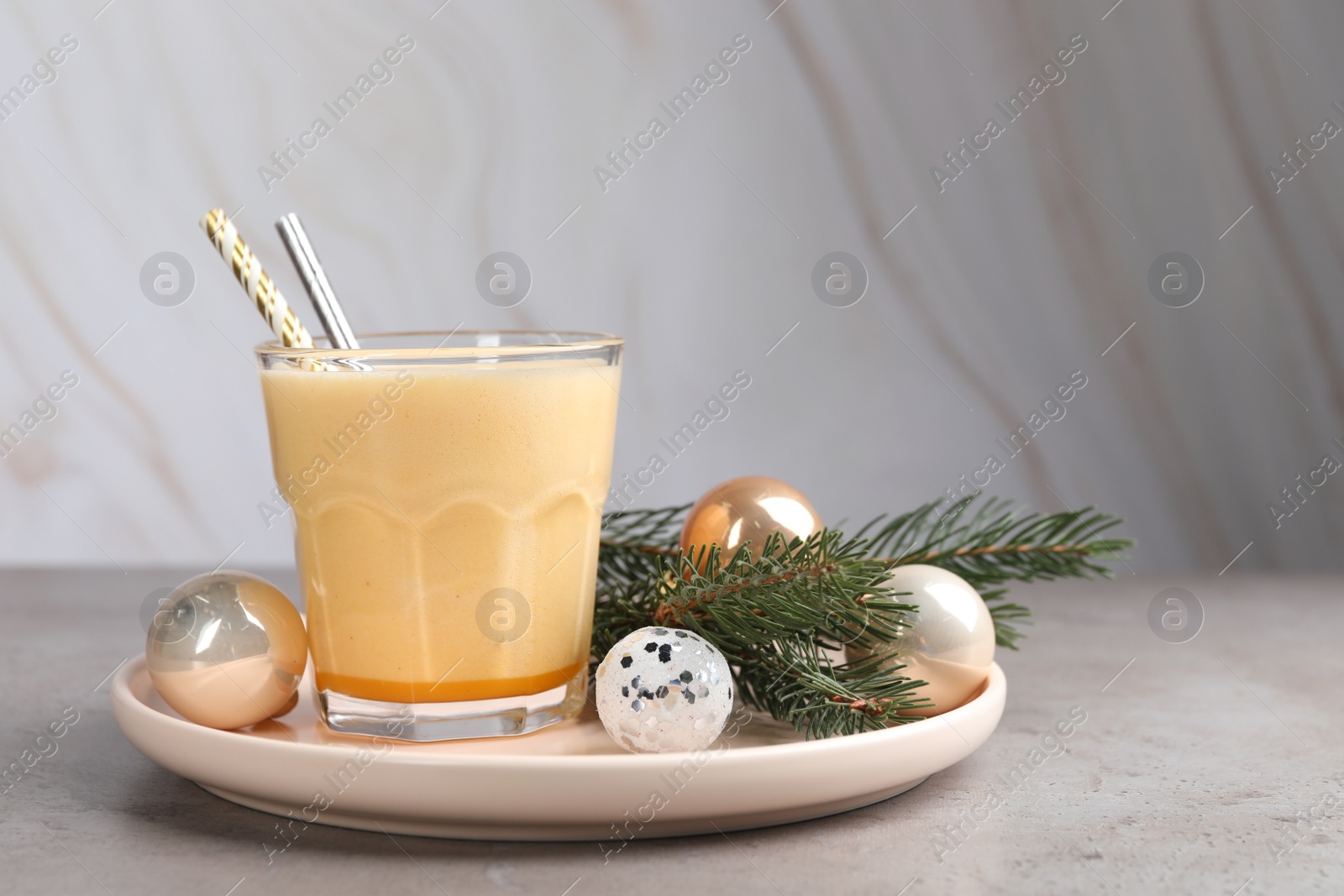 Photo of Glass of delicious eggnog on gray table, space for text