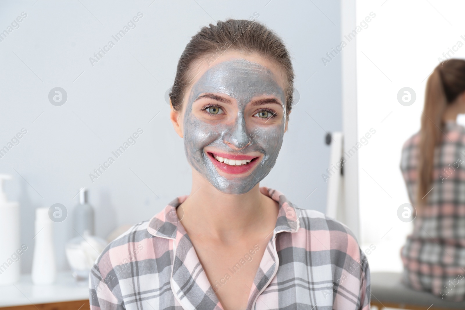 Photo of Young woman with cleansing mask on her face in bathroom. Skin care