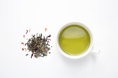 Photo of Green tea leaves and cup of hot beverage on white background, flat lay