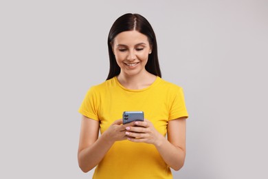 Photo of Young woman using smartphone on grey background