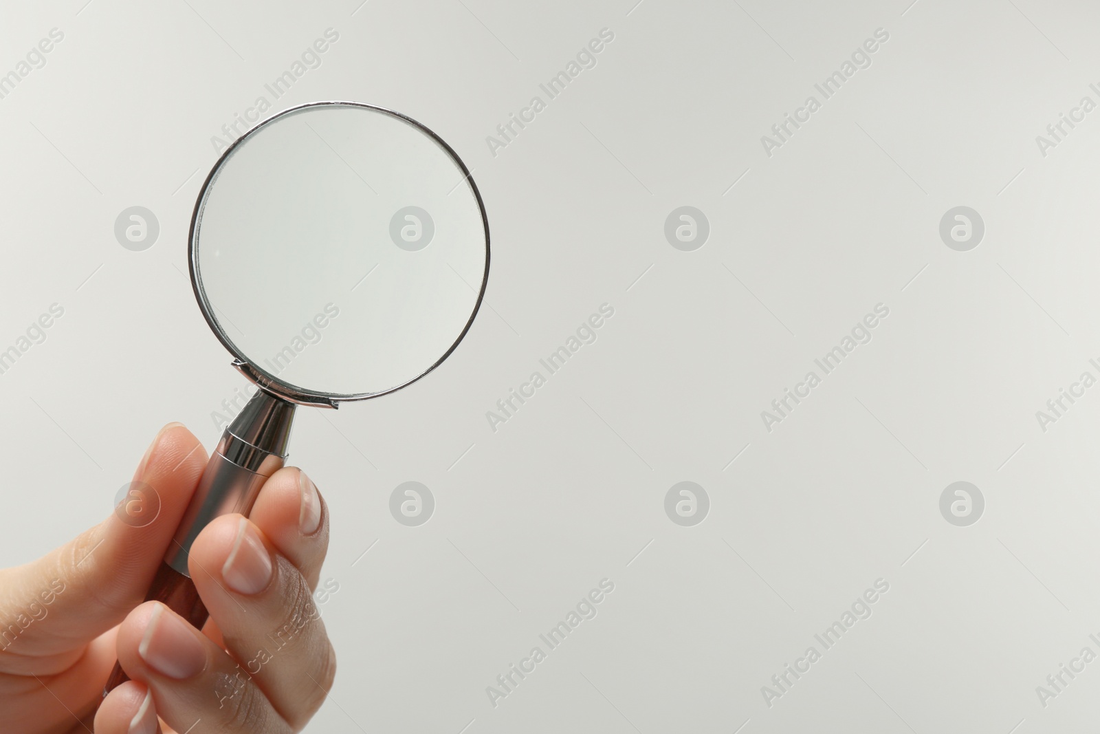 Photo of Woman holding magnifying glass on white background, closeup. Space for text