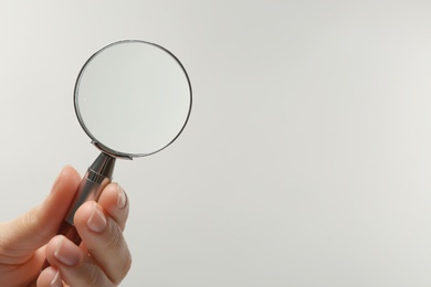 Photo of Woman holding magnifying glass on white background, closeup. Space for text