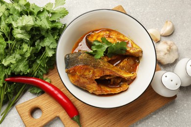 Photo of Tasty fish curry and ingredients on grey textured table, flat lay. Indian cuisine