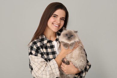 Happy woman with her cute cat on light grey background