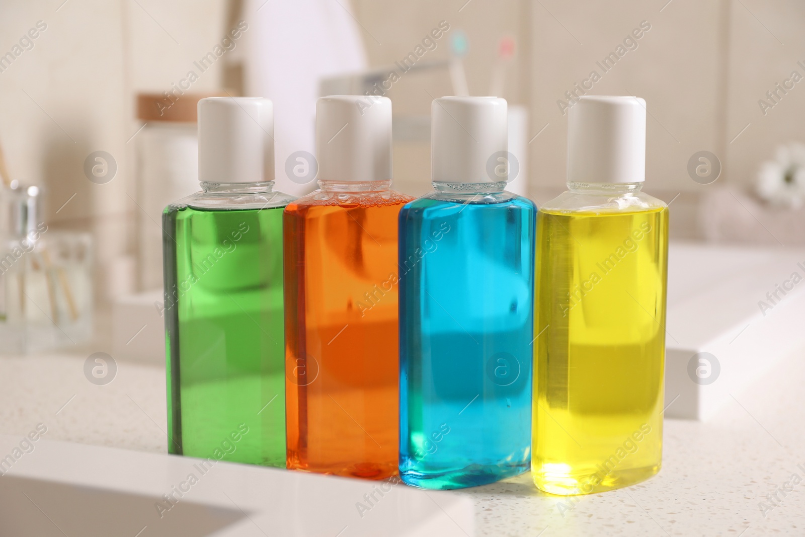 Photo of Fresh mouthwashes in bottles on countertop near sink, closeup