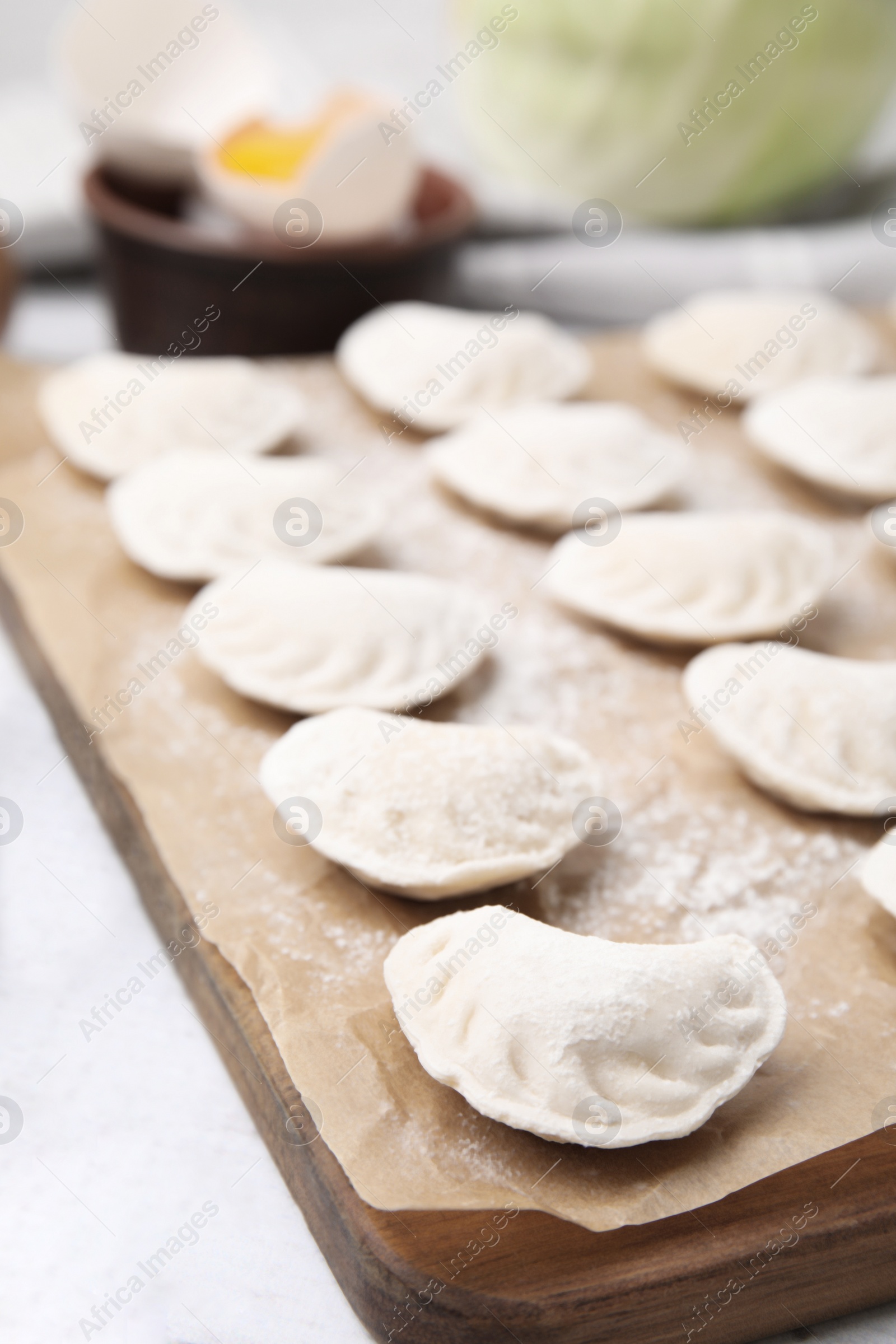 Photo of Raw dumplings (varenyky) with tasty filling on white wooden table, closeup