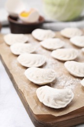 Photo of Raw dumplings (varenyky) with tasty filling on white wooden table, closeup