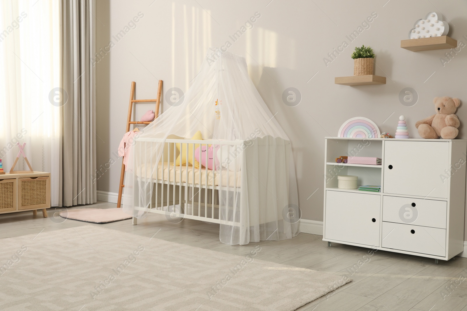 Photo of Cozy baby room with crib and other furniture. Interior design