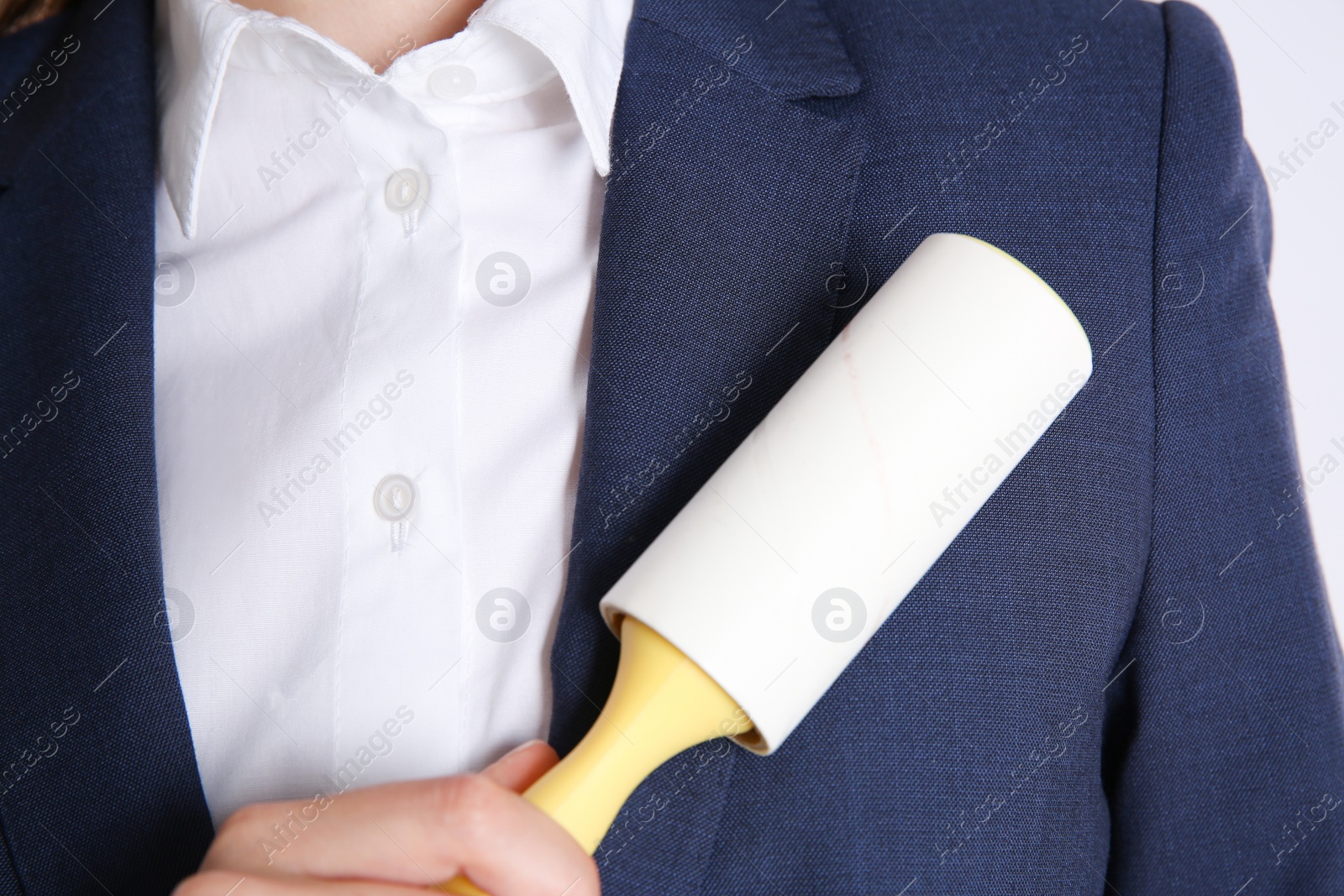 Photo of Woman cleaning dark blue jacket with lint roller, closeup