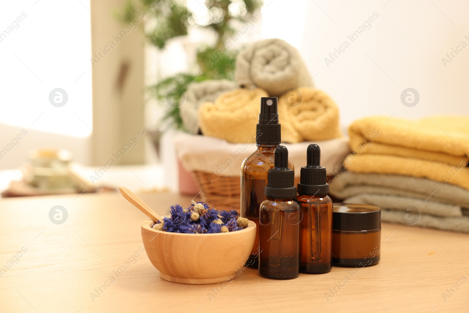 Photo of Dry flowers, bottles of essential oils and jar with cream on wooden table indoors. Spa time