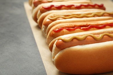 Photo of Tasty fresh hot dogs on grey table, closeup. Space for text