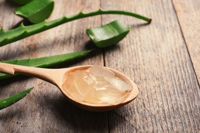 Photo of Spoon with aloe vera gel on wooden background