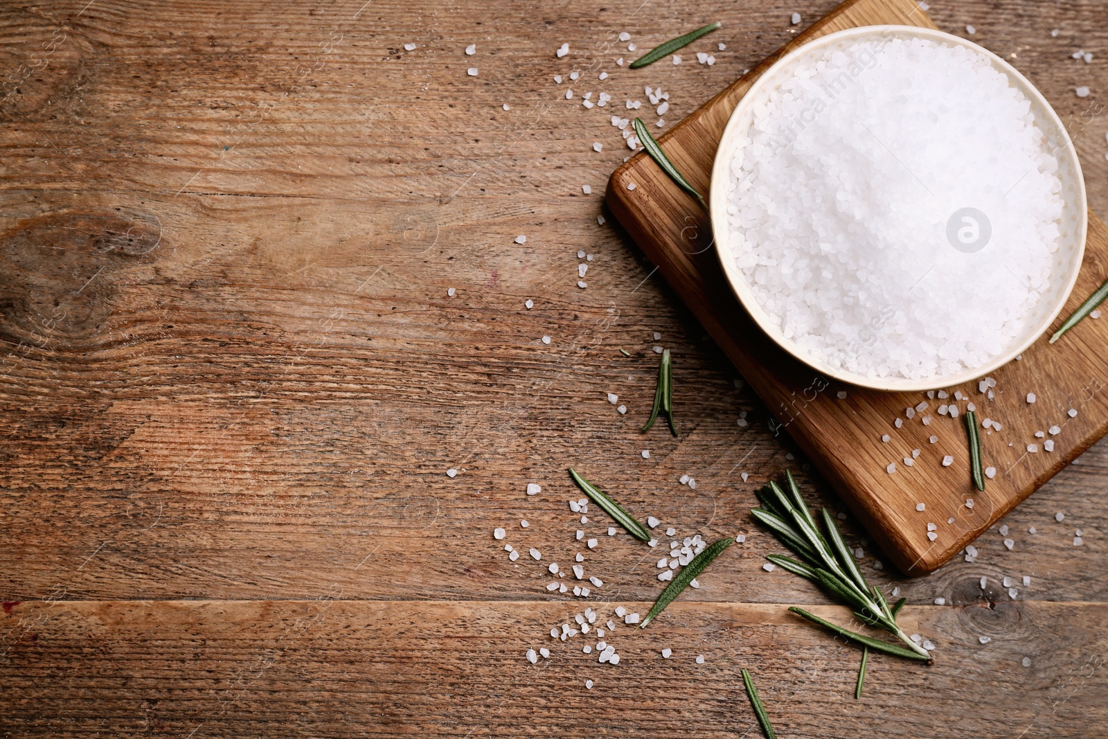 Photo of Natural salt and rosemary on wooden table, flat lay. Space for text