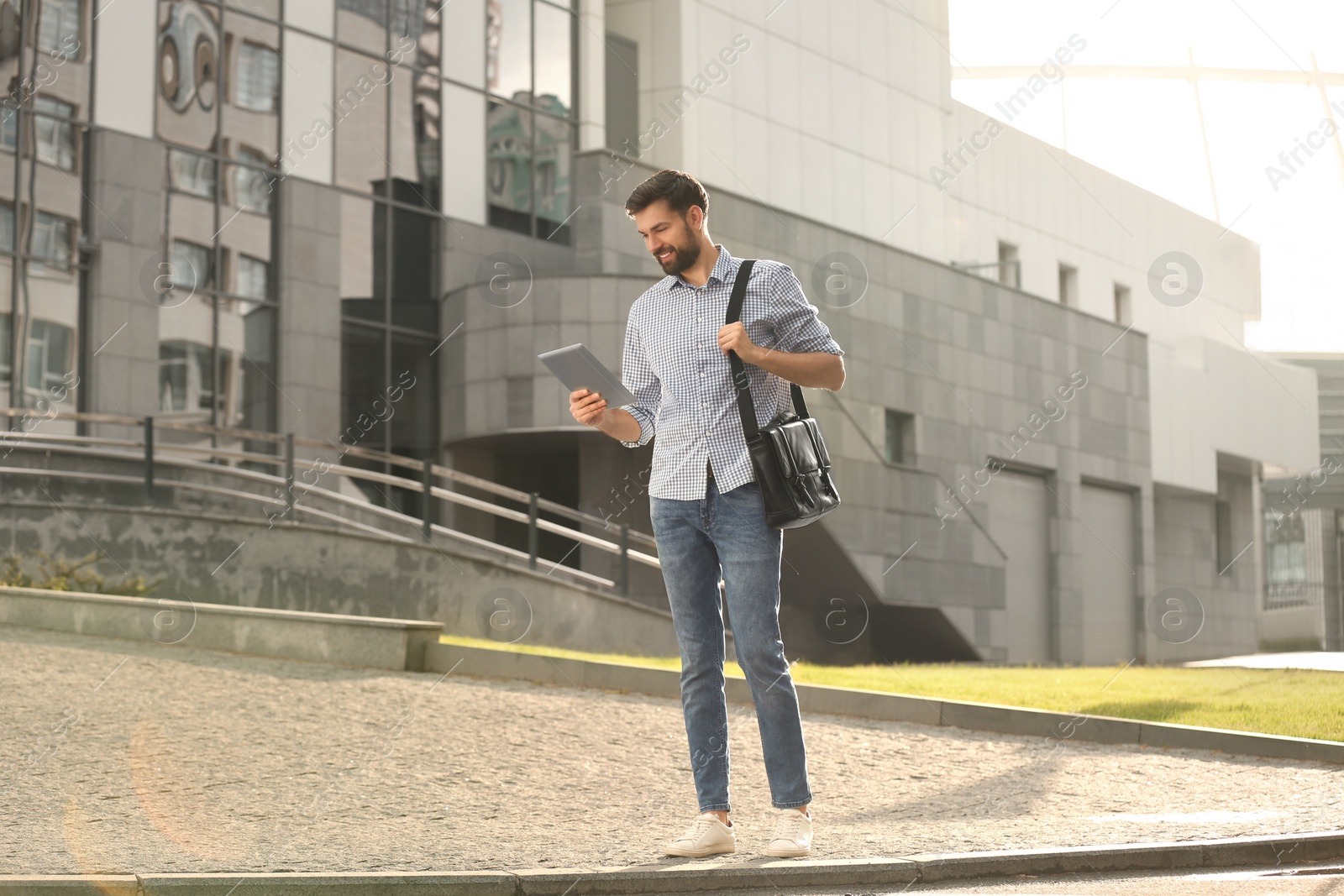 Photo of Handsome man working with tablet on city street