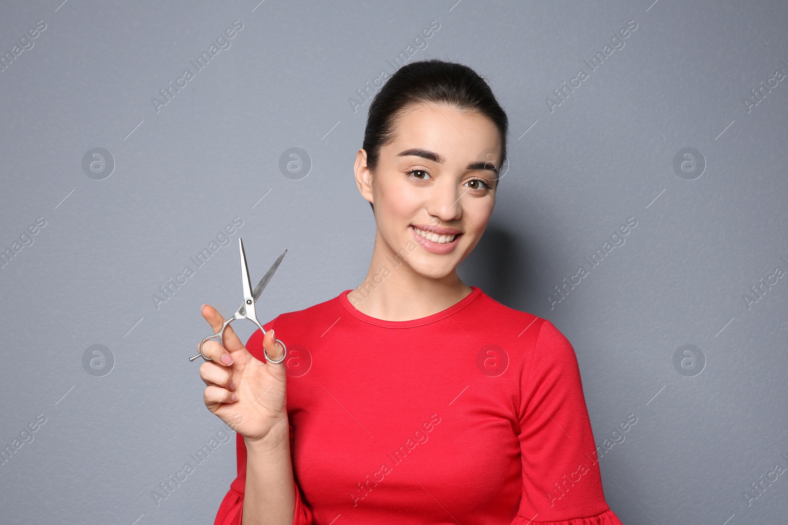 Photo of Professional hairdresser with scissors on color background