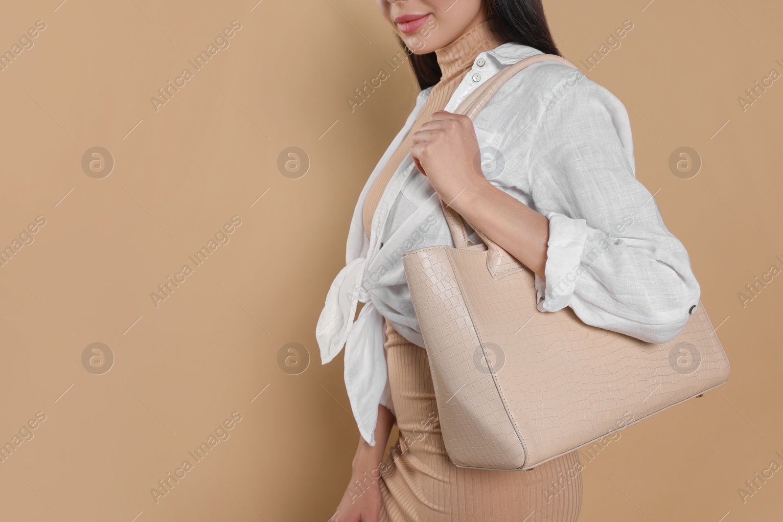 Photo of Young woman with stylish bag on beige background, closeup. Space for text