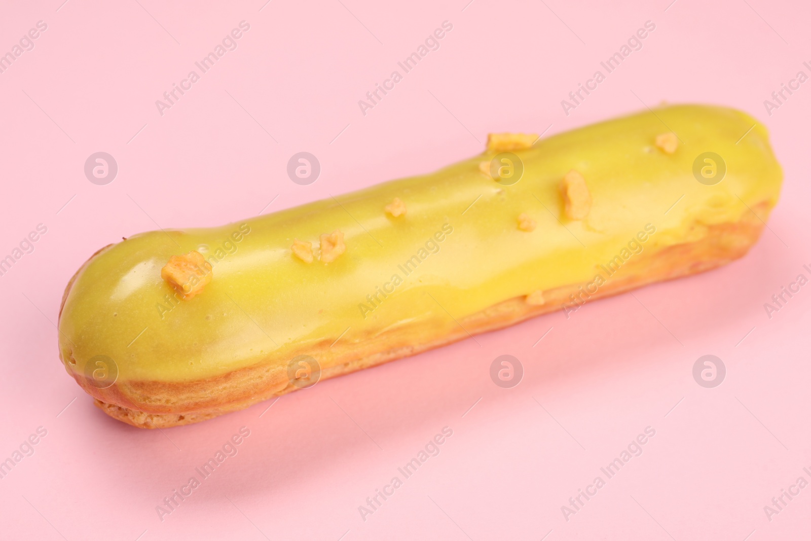 Photo of Delicious eclair covered with glaze on pink background