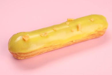 Delicious eclair covered with glaze on pink background