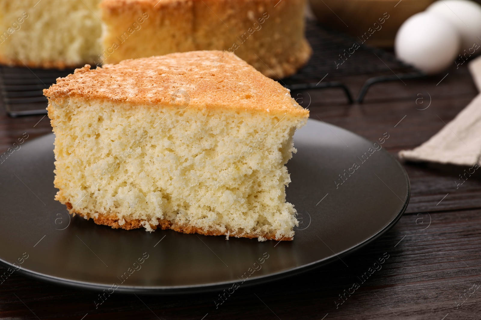 Photo of Plate with piece of tasty sponge cake on wooden table, closeup