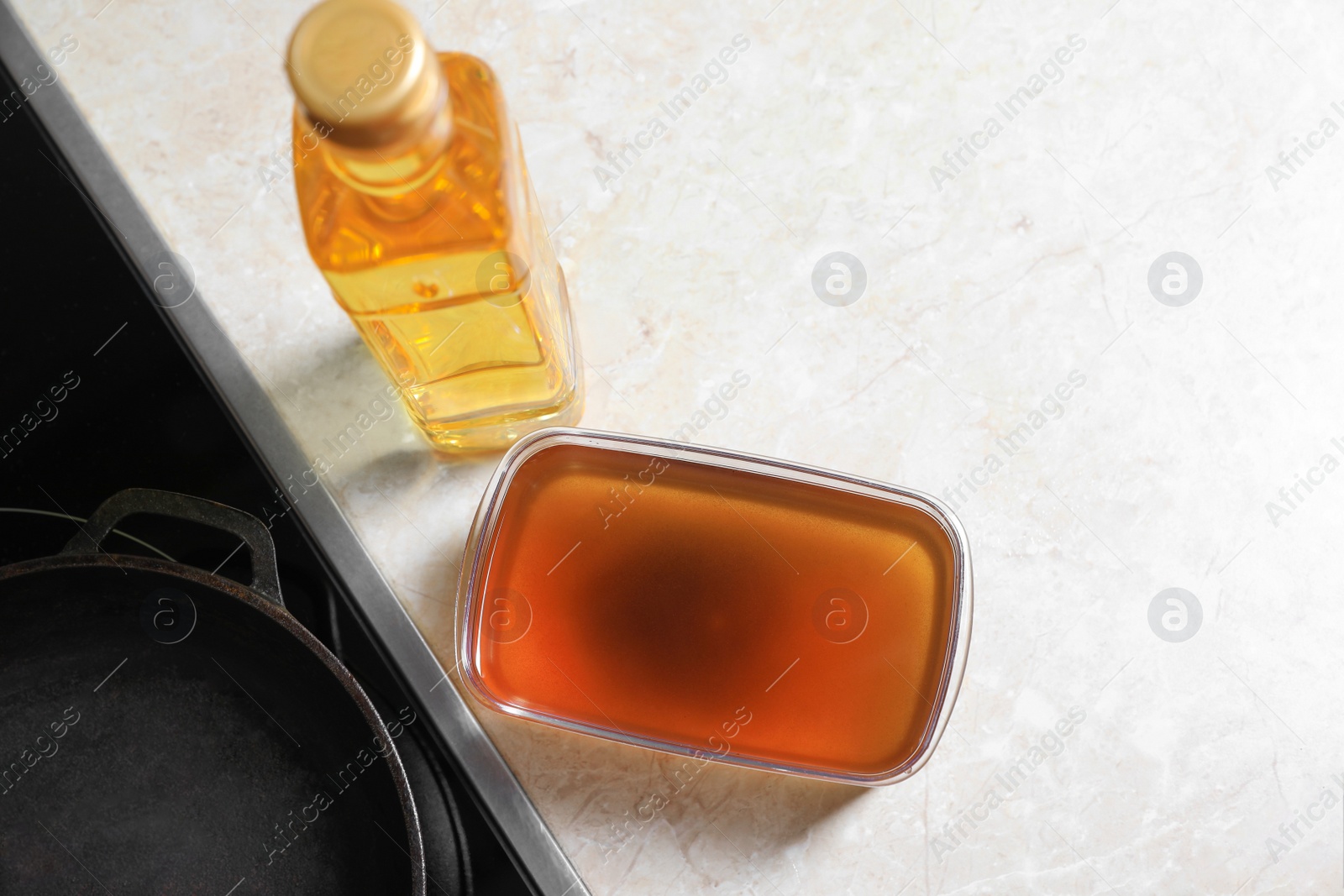 Photo of New and used cooking oil near stove on kitchen counter