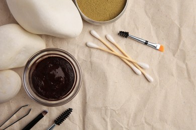 Flat lay composition with eyebrow henna and tools on crumpled paper. Space for text