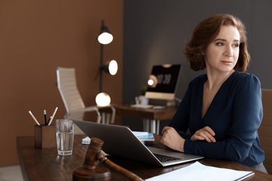 Photo of Female lawyer working with laptop at table in office