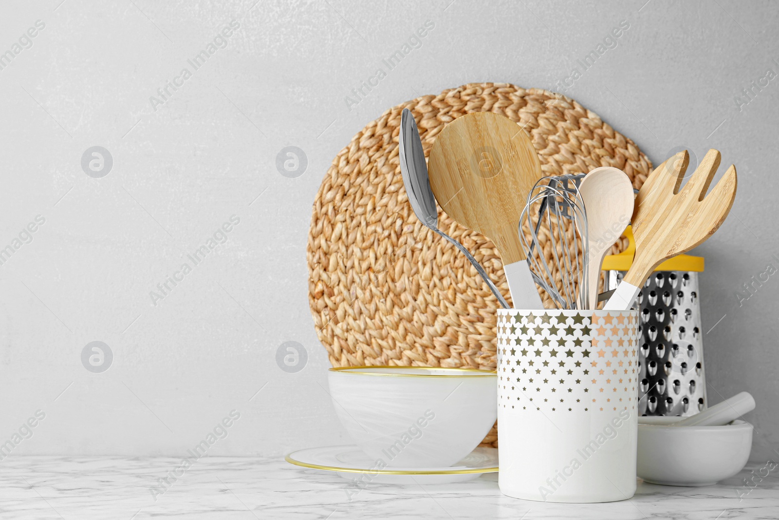 Photo of Different kitchen utensils on table against light background. Space for text