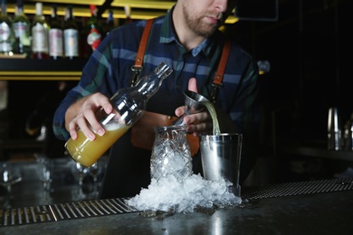 Photo of Barman making tropical cocktail at counter in pub, closeup