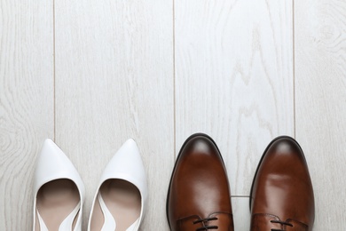 Photo of Wedding shoes on white wooden floor, flat lay. Space for text