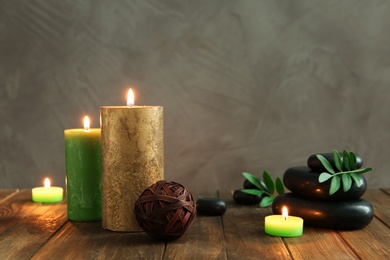 Photo of Beautiful composition with spa stones and candles on wooden table. Space for text