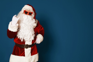 Photo of Authentic Santa Claus wearing sunglasses on blue background. Space for text