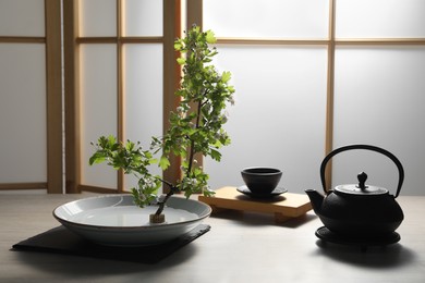 Photo of Stylish ikebana as house decor. Beautiful fresh branch and tea set on wooden table