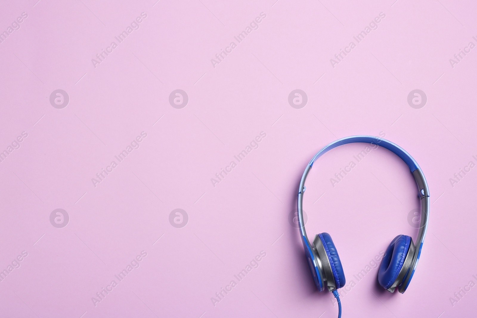 Photo of Stylish headphones on color background, top view. Space for text