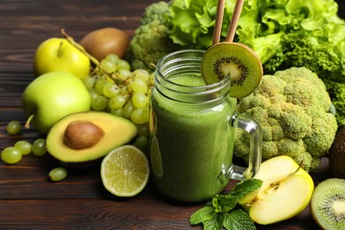 Photo of Green smoothie in mason jar and fresh ingredients on wooden table