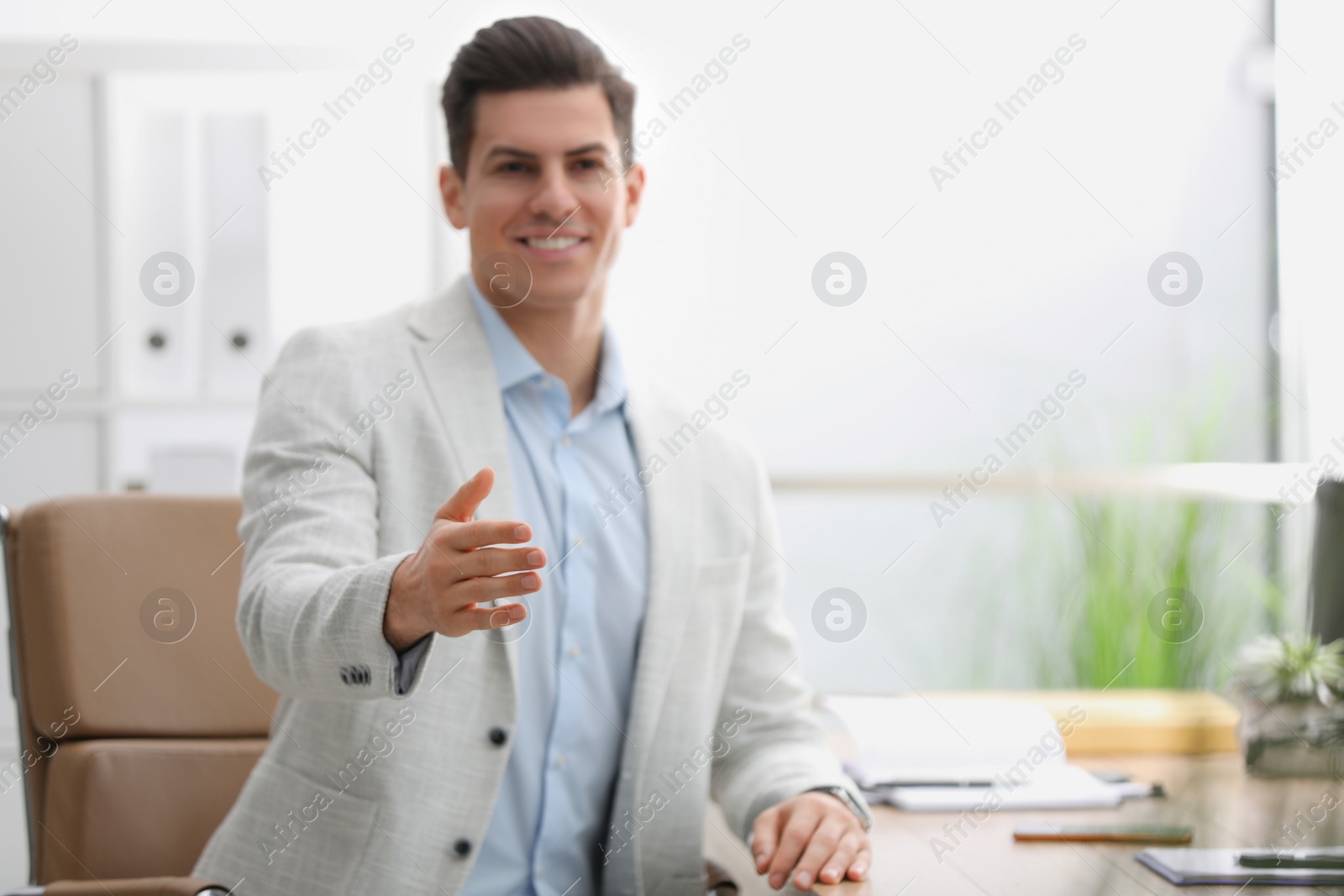 Photo of Businessman offering handshake in office, focus on hand. Space for text