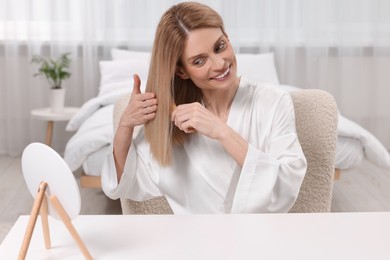 Beautiful woman brushing her hair at vanity in bedroom