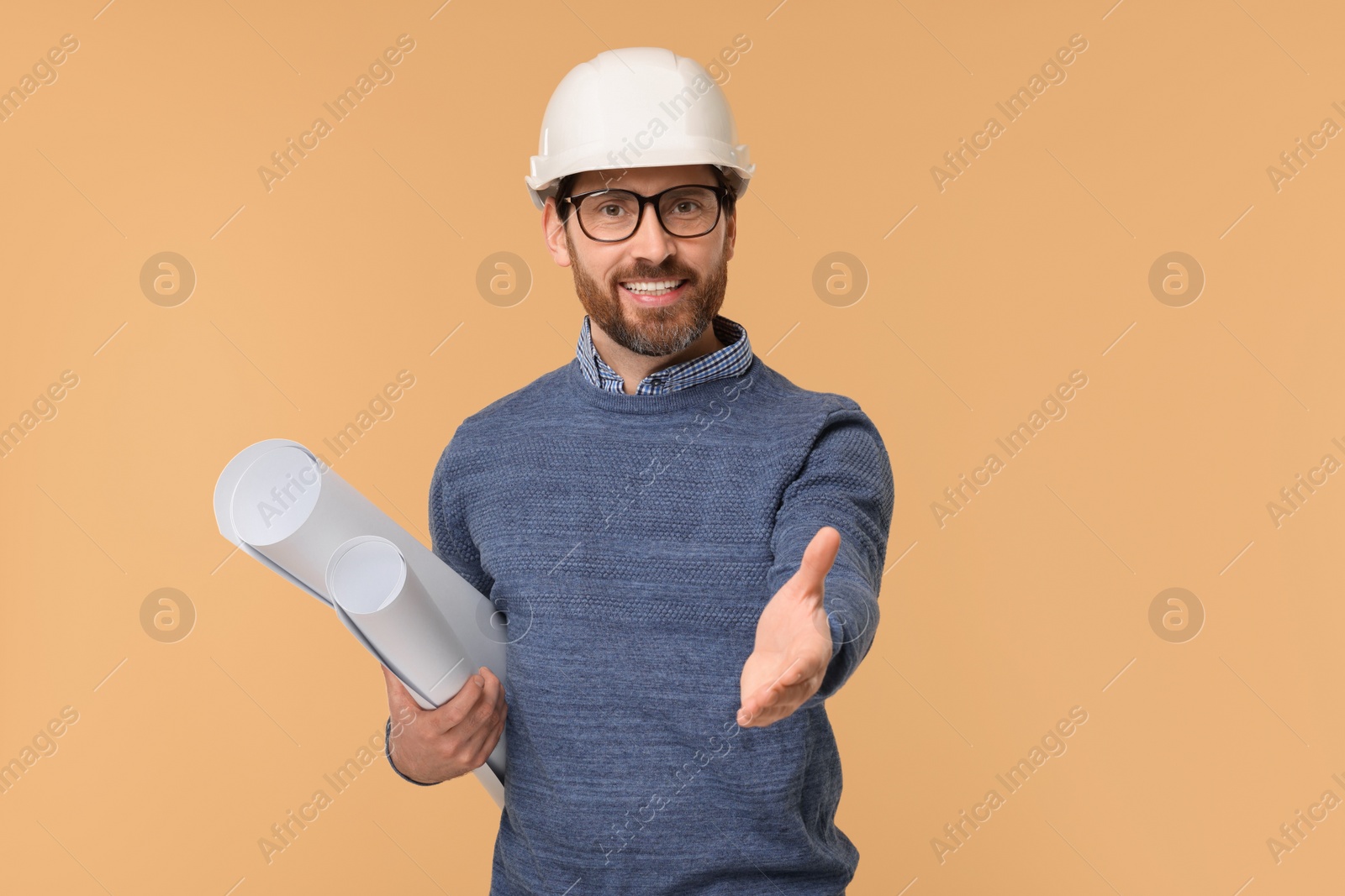 Photo of Architect in hard hat with drafts greeting someone on beige background