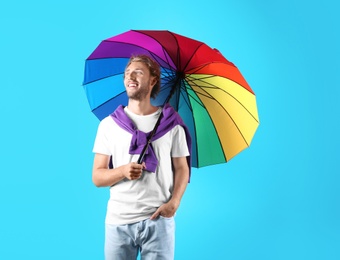 Man with rainbow umbrella on color background