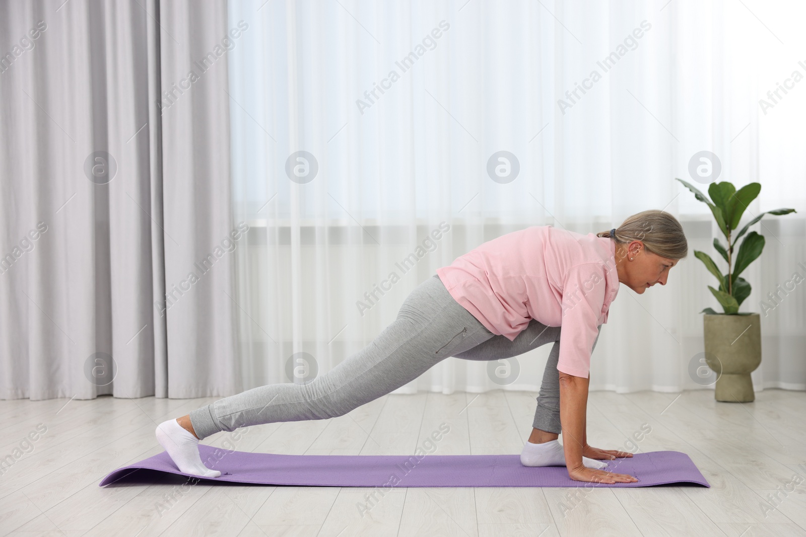 Photo of Senior woman practicing yoga on mat at home