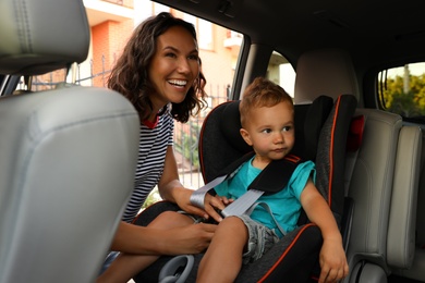 Woman fastening her son with car safety belt. Family vacation