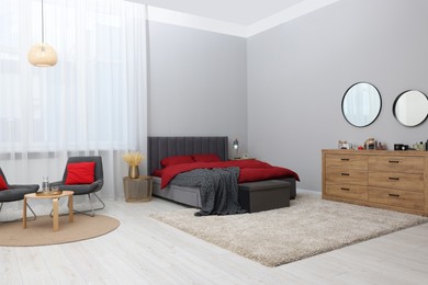 Photo of Stylish bedroom with comfortable bed and wooden chest of drawers. Interior design