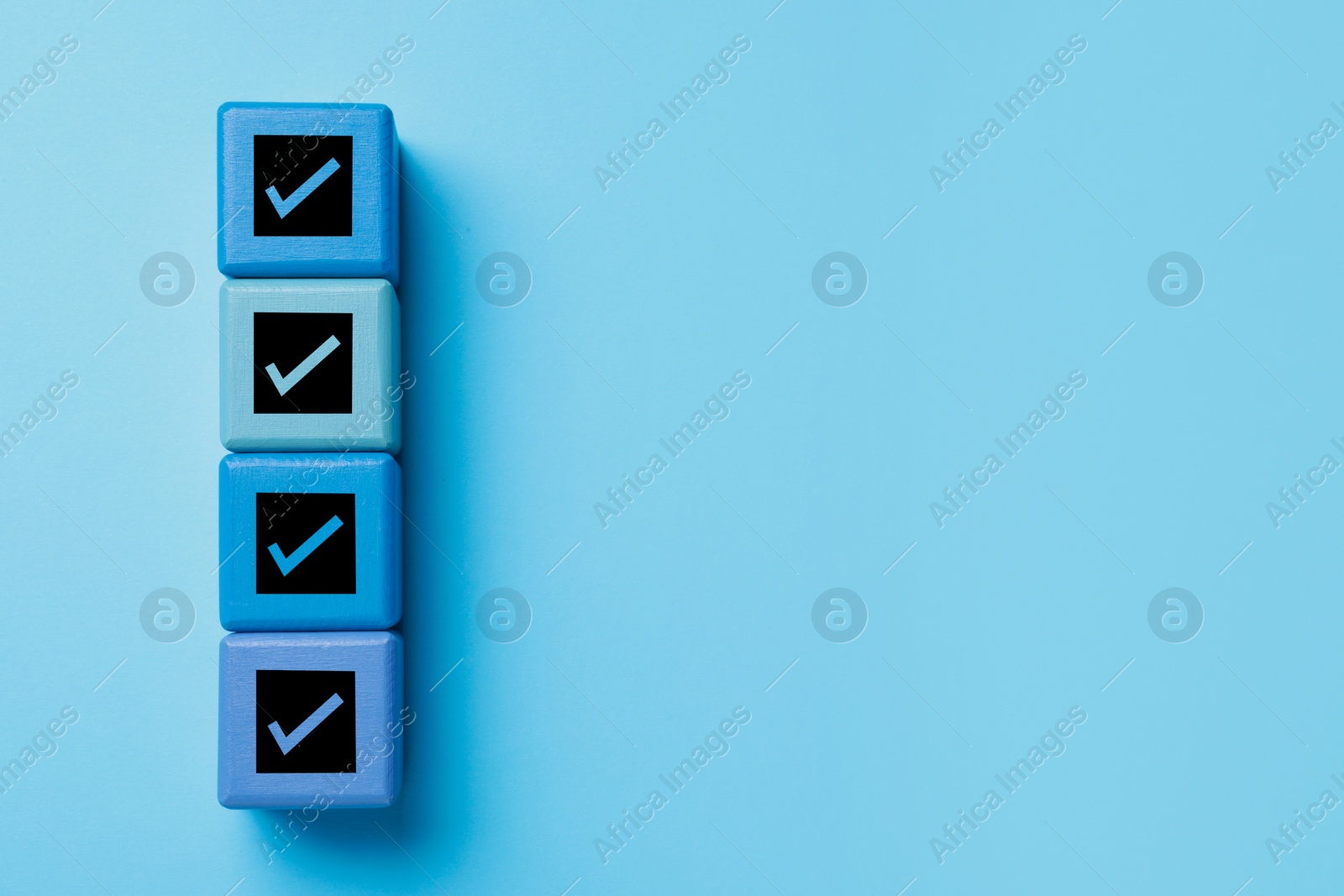 Image of Cubes with check marks on light blue background, top view. Space for text