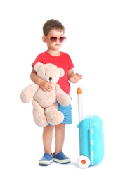 Photo of Cute little boy with toy and blue suitcase on white background