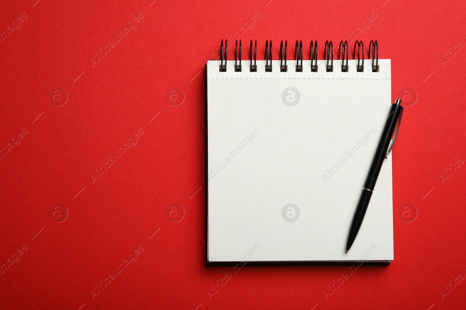 Photo of Stylish open notebook and pen on red background, top view. Space for text