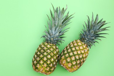 Photo of Whole ripe pineapples on light green background, flat lay