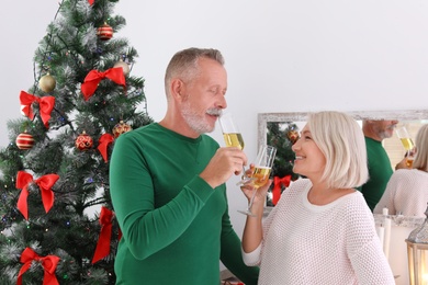 Photo of Mature couple with glasses of champagne at home. Christmas celebration