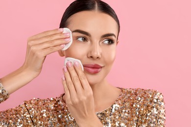 Beautiful woman removing makeup with cotton pads on pink background