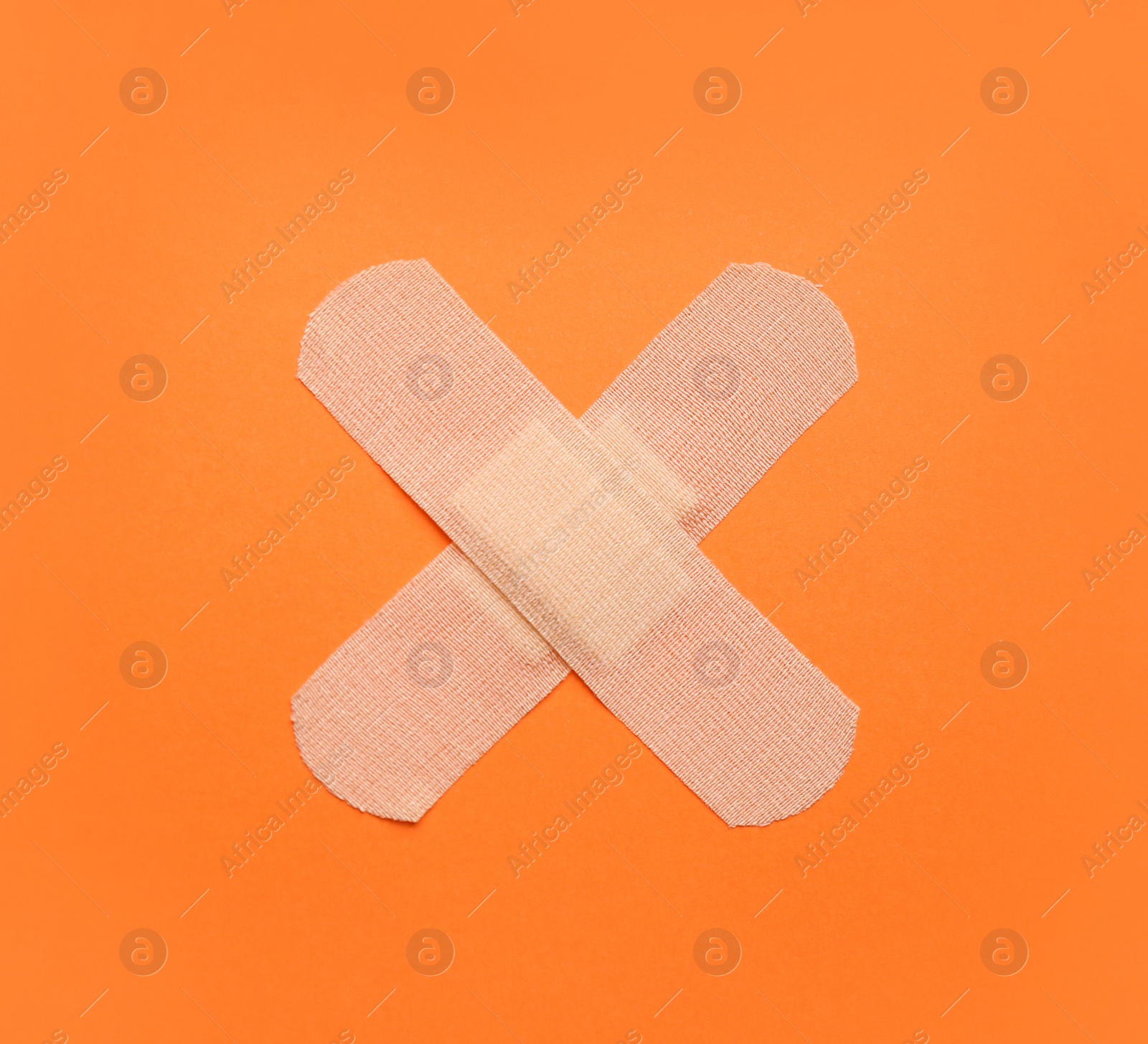 Photo of Sticking plasters on orange background, top view