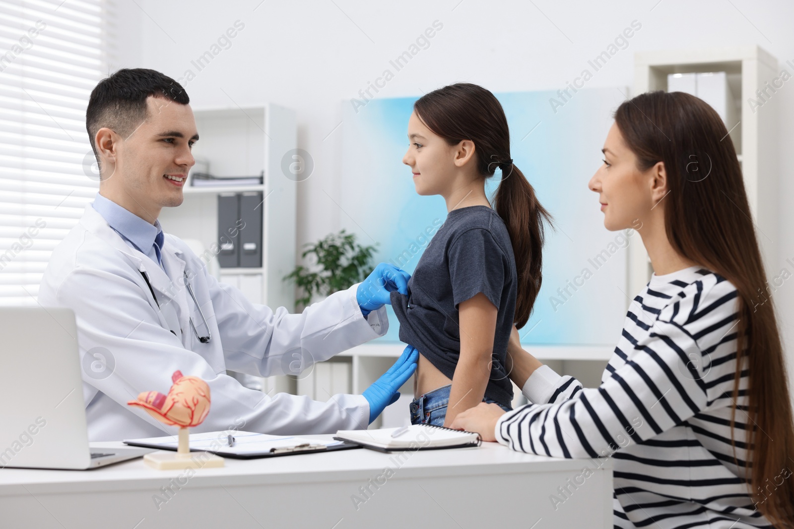 Photo of Gastroenterologist examining girl with stomach ache in clinic