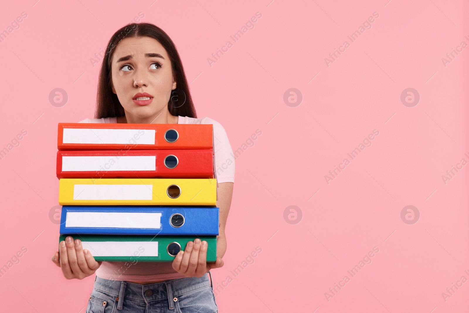 Photo of Frustrated woman with folders on pink background, space for text